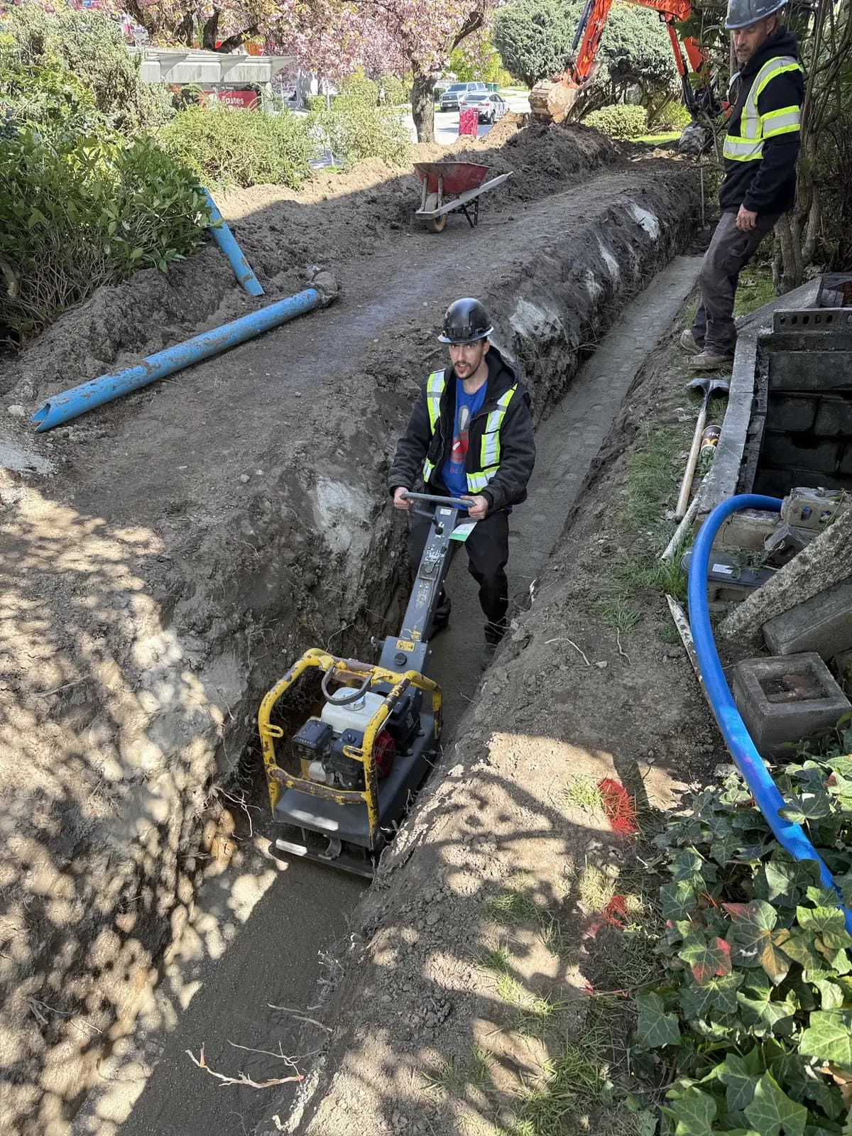 Technicians coordinating controlled excavation beside a residential building